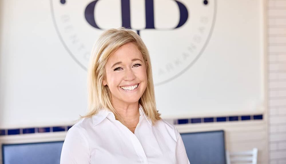 blonde woman in front of the Buttered Biscuit logo