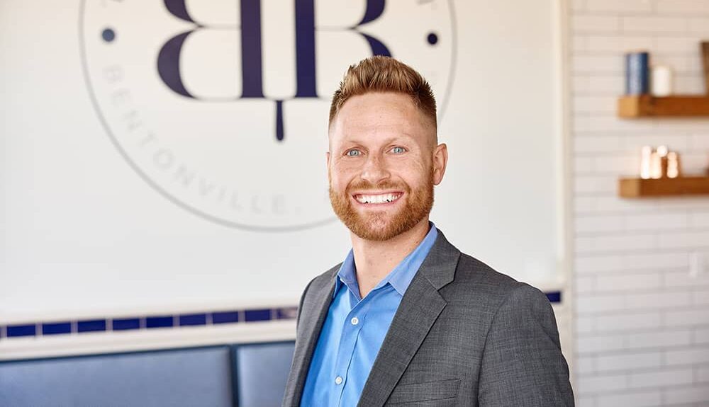 red headed man in front of the Buttered Biscuit logo