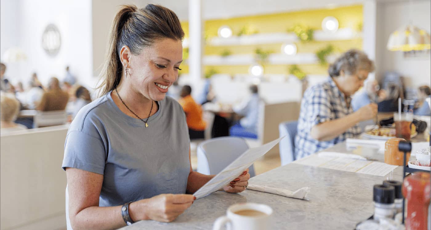 woman smiling and holding a menu at the buttered biscuit counter