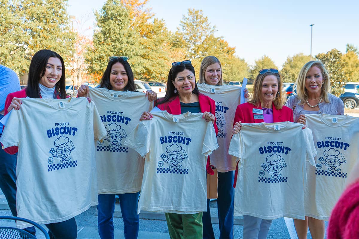 6 women smiling and holding project biscuit tshirts