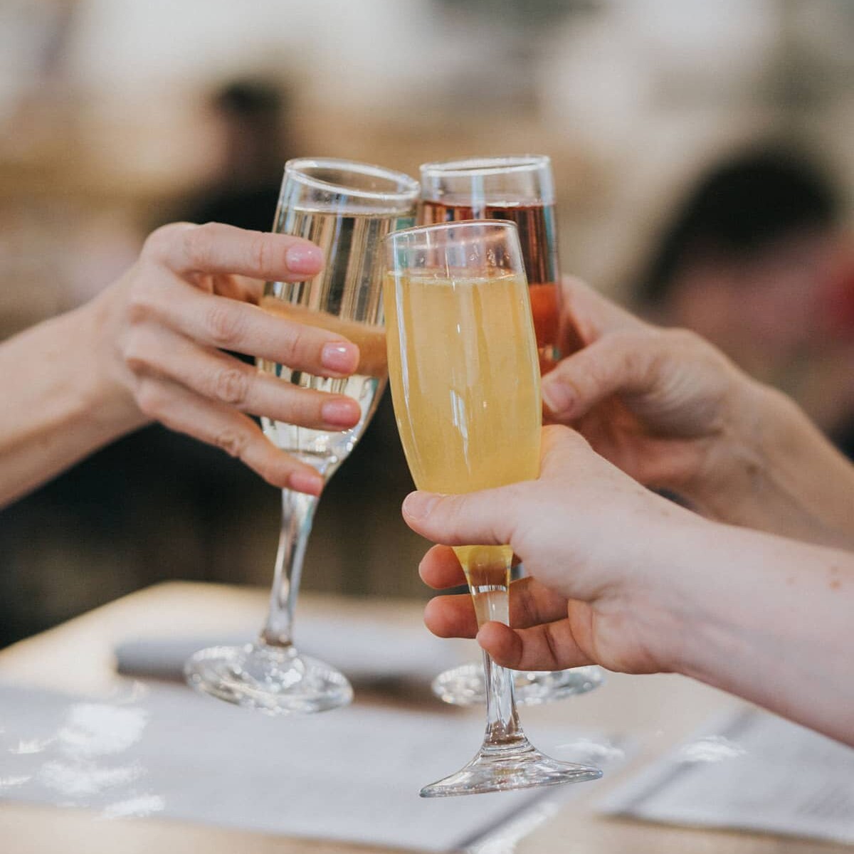Three people toasting, celebrating, and having fun with flutes of delicious drinks